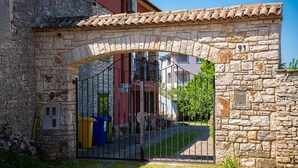 Un arc en pierre mène à un bâtiment doté d’un toit en tuiles et sur lequel on peut voir le chiffre « 91 » peint sur le mur.