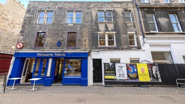 A building with a blue storefront labeled "Patisserie Valerie" and a white building with posters. - JOIVY Rose Street Hideaway (Edinburgh)