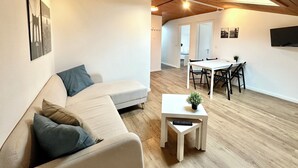 Una sala de estar moderna con un sofá, una pequeña mesa con un teclado y un comedor con sillas y una mesa.