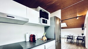 Una cocina moderna con armarios blancos, un refrigerador de acero inoxidable, un microondas y una cafetera.