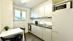 Una cocina moderna con armarios blancos, un microondas integrado y un ventanal con vistas a la ciudad.