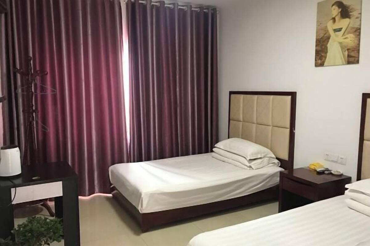 A hotel room with a bed, bedside table, lamp, and curtains.