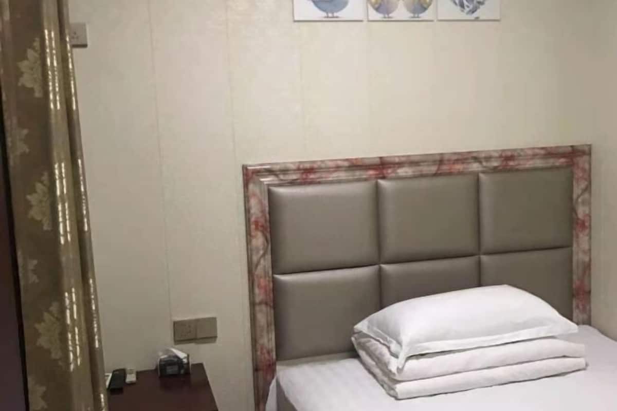 A hotel room with a bed, a nightstand, and a wall-mounted clock.