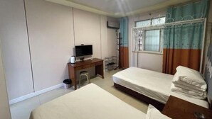 Een slaapkamer met twee bedden, een bureau met een televisie en een garderobe.