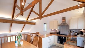 A modern kitchen with wooden beams, white cabinets, and a dining area with a wooden table and chairs.