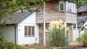 Una casa de dos pisos con fachada de piedra, un piso superior de madera y un piso inferior blanco.
