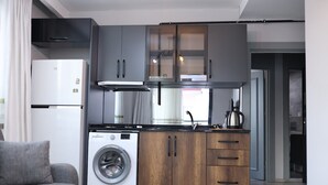 Cocina funcional con lavadora, muebles grises y encimera de madera.