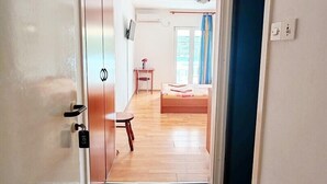 Un passadís que condueix a un dormitori amb un llit, una taula petita i una cadira.