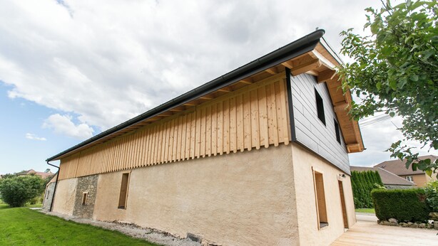 Ein modernes Gebäude mit flachem Dach, Holzverkleidung und einem gepflasterten Einfahrtsweg.