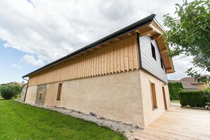 A modern building with a flat roof, wooden siding, and a paved driveway. - Large gîte for 12 to 14 people, ideally located in the heart of the Jura mountains. (Cuvier)