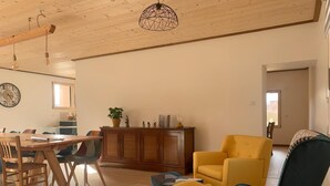 Ein großzügiger Wohnbereich mit Holzboden, einem Esstisch mit Stühlen, einem gelben Sessel, einem blauen Sofa und einer Kommode mit Dekoration.