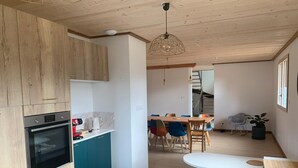 Eine moderne Küche mit Holzausstattung, integriertem Backofen und einer Essecke mit Wendeltreppe.