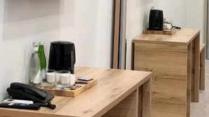 A hotel room with a wooden desk, a telephone, and a coffee maker.