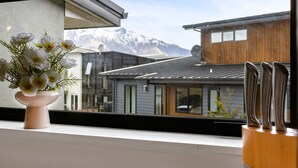 Une maison moderne, avec une façade en bois et une vue sur des montagnes enneigées, visible à travers une fenêtre.