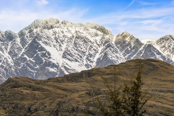 Un paysage montagneux aux sommets enneigés, avec un premier plan constitué d’un terrain rocheux.