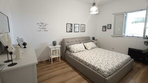 Une chambre à coucher comprenant un lit, des tables de chevet, une lampe suspendue, une fenêtre et des éléments de décoration murale.