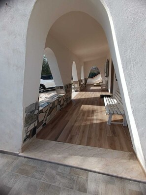 A covered outdoor area with stone and wood flooring, white walls, and a bench. - Villamar within walking distance of the sea. (Arenella)