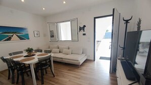 Un salon moderne comprenant un coin repas, un canapé, un téléviseur et une grande fenêtre.