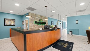 A reception desk with a stone wall backdrop, a computer, and a sign that reads "RESORT". - Close to Disney, Far from Pricey! (Kissimmee)