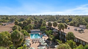 A resort with a swimming pool, lounge chairs, and palm trees. - Park Thrills + Poolside Vibes = Vacation Goals! (Kissimmee)