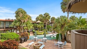 A courtyard with outdoor seating, palm trees, and a pool. - Park Thrills + Poolside Vibes = Vacation Goals! (Kissimmee)