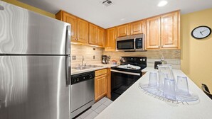 A modern kitchen with stainless steel appliances, wooden cabinets, and a microwave. - Park Thrills + Poolside Vibes = Vacation Goals! (Kissimmee)
