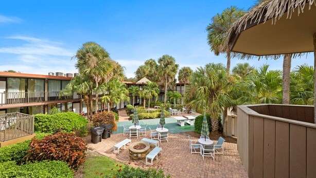 A courtyard with a pool, lounge chairs, and palm trees. - Park-Hopping Made Easy | 2BR Retreat Near Disney & Universal (Kissimmee)