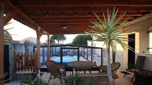A covered patio with wicker furniture, a pool, and a view of the neighborhood. - Magnificent villa with heated pool near La Citée (Carcassonne)