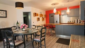 A modern kitchen with grey cabinets, a wooden countertop, and a dining area with a glass table and chairs. - Magnificent villa with heated pool near La Citée (Carcassonne)