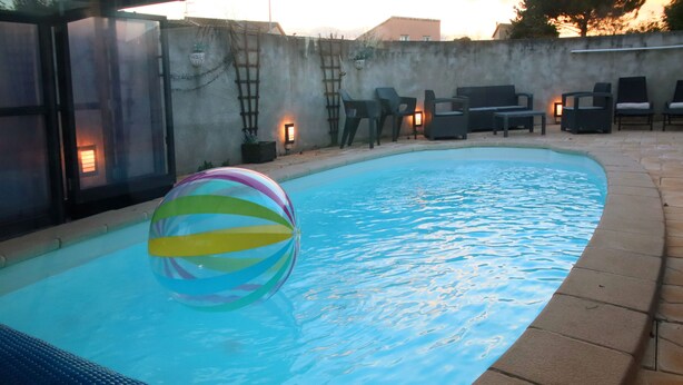 A swimming pool with a colorful ball, surrounded by chairs and a wall with a ladder. - Magnificent villa with heated pool near La Citée (Carcassonne)