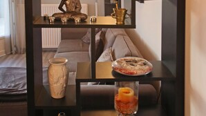 A modern living room with a black shelving unit displaying various decorative items, a sofa, and a wine bottle. - Magnificent villa with heated pool near La Citée (Carcassonne)