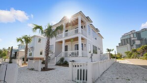 Una proprietà fronte spiaggia con una casa a due piani, un portico coperto e una spiaggia sabbiosa.