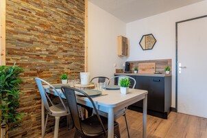 Una cocina funcional con pared de madera, una mesa de comedor con sillas y una pequeña encimera con fregadero y armarios.