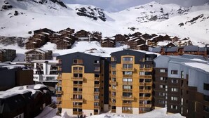 A snow-covered mountain village with wooden chalets and modern multi-story buildings. - Cimes des caron  (Les Belleville)