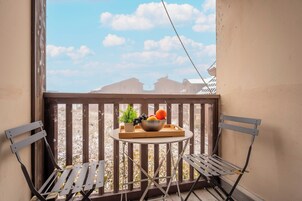 Un balcone con un tavolo e due sedie, una ciotola di frutta e una pianta in vaso.