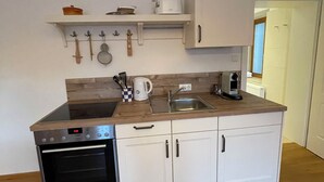 A compact kitchen with white cabinets, a built-in oven, and a wooden countertop. - Gästehaus Burgblick im Weinhaus Pachler (Hochburg-Ach)