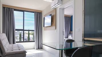 A modern living room with a glass coffee table, a sofa, and a TV mounted on the wall.