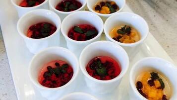 A tray of small white cups with various food items, possibly desserts, arranged on a white plate.