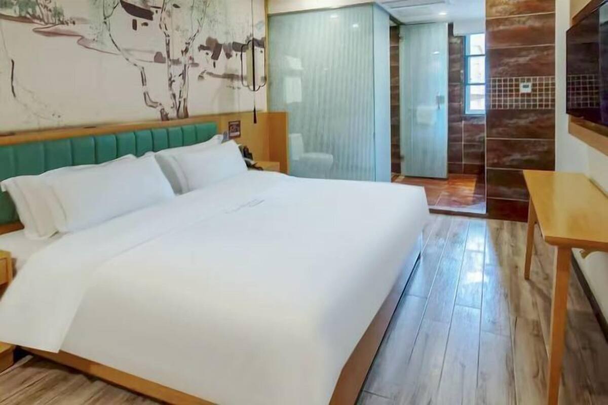 Ein Hotelzimmer mit einem großen Bett, einem Holzkopfende, einem kleinen Tisch und einem Fernseher.