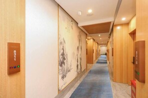 A hotel corridor with wooden walls, a blue carpet, and a long hallway with doors on one side.