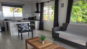 Ein modernes Wohnzimmer mit einem Holztisch, einer Couch und einer Küchenzeile mit Esstisch und Stühlen.