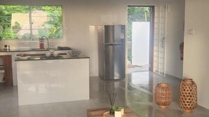 Eine moderne Küche mit einem Edelstahlkühlschrank, einem Essbereich mit Holztisch und Blick ins Grüne.