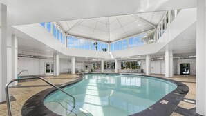 An indoor swimming pool with a clear view of the sky through large windows, surrounded by white walls and columns. - GS Plantation West 1339 (Gulf Shores)