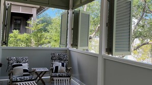 Une véranda avec deux fauteuils, une petite table et un ventilateur de plafond.