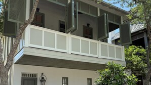 Une maison à deux étages avec un porche à l’avant, une boîte aux lettres et un petit arbre dans le jardin.