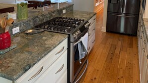 Une cuisine moderne dotée de plans de travail en granit, d’appareils électroménagers en acier inoxydable et d’un revêtement de sol en bois.