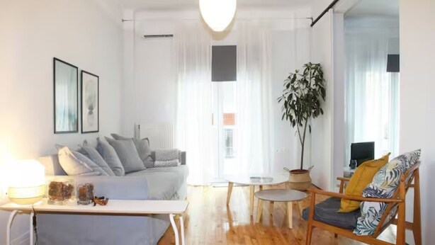Una sala de estar moderna con un sofá, una mesa de centro, una silla de madera y una planta en maceta.