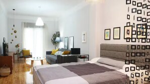 Una habitación de hotel moderna con una cama grande, un escritorio, un sofá y un comedor.
