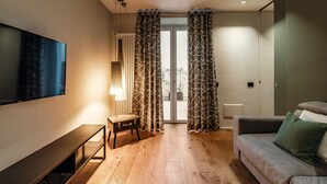 A modern living room with a flat-screen TV, a bench, a sofa, and a sliding glass door with patterned curtains. - Hidden Lodge (Como)