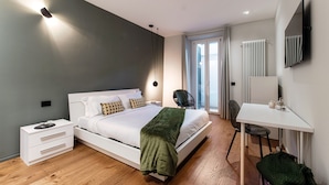 A modern bedroom with a large bed, bedside tables, a desk, and a chair. - Hidden Lodge (Como)